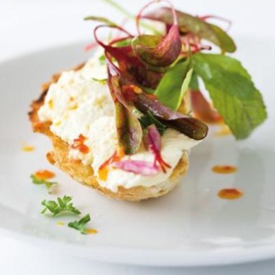 Marinated feta on golden toasts topped with fresh leaves