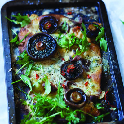 Pizza with brown mushrooms, anchovies, blue cheese and rocket